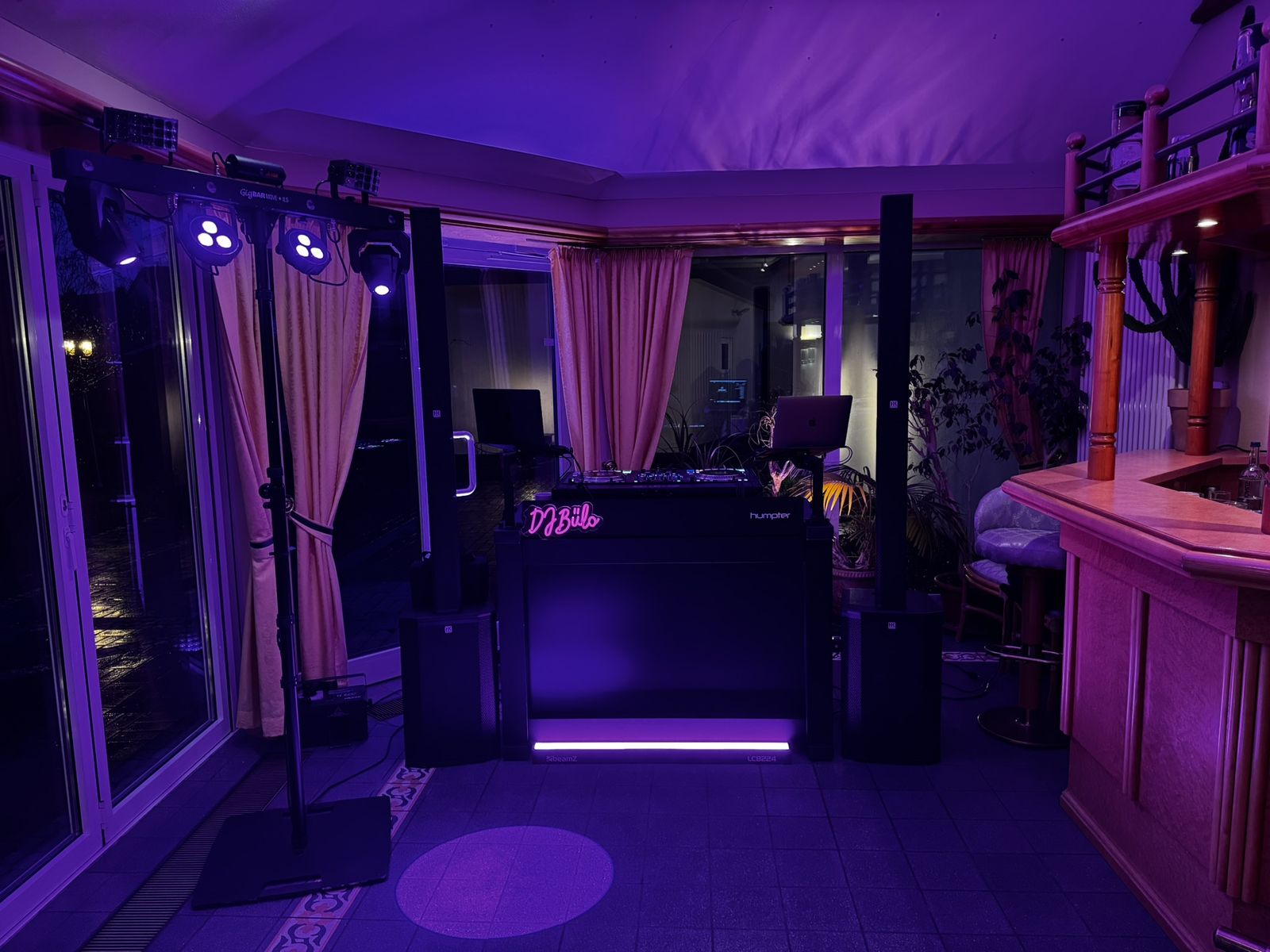 DJ-Aufbau von DJ Bülo vor Veranstaltungsbeginn: Humpter-DJ-Pult mit Controller und zwei MacBooks, Säulen-Lautsprecher mit Subwoofern und Lichtanlage mit Moving Heads