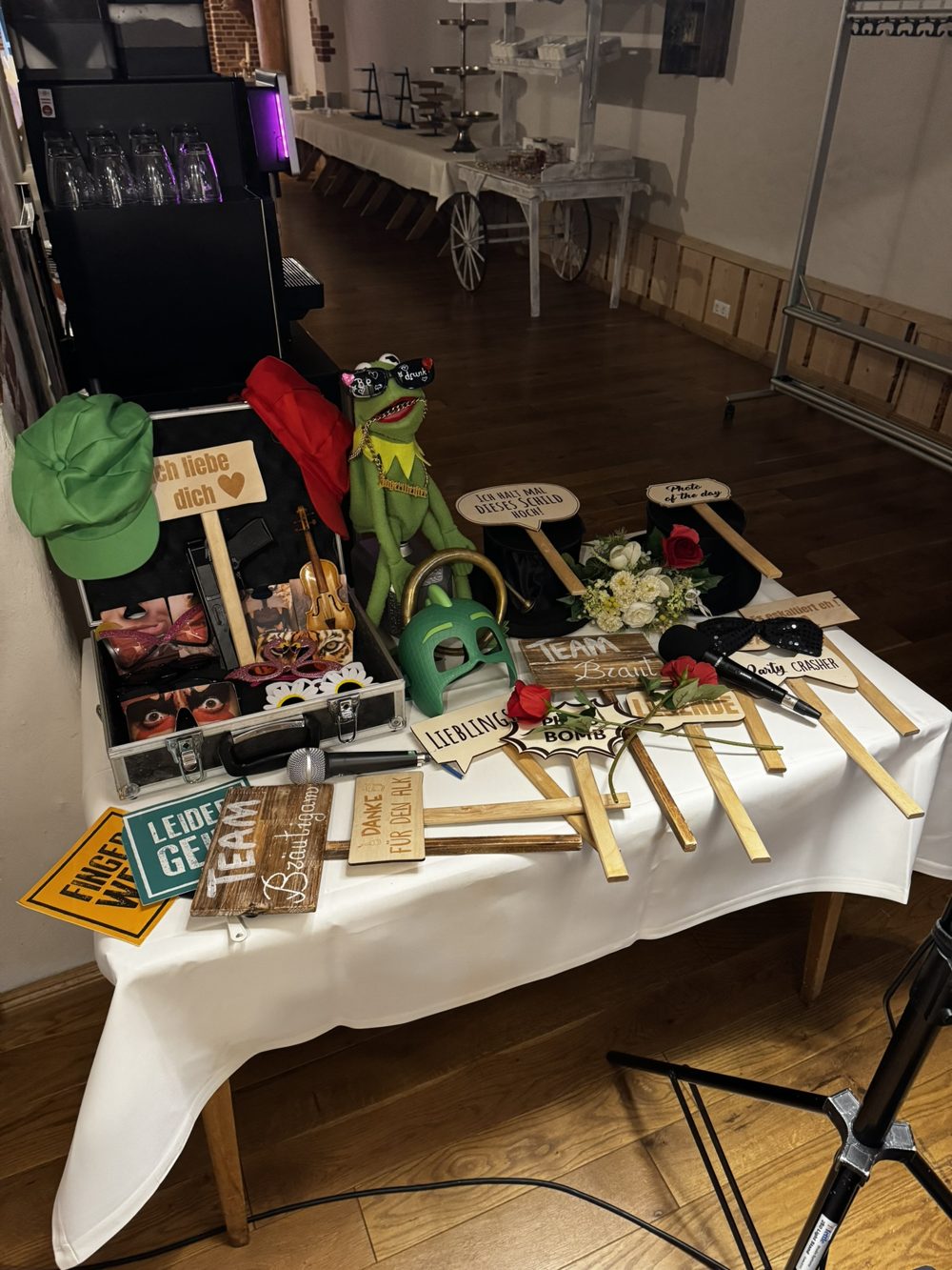 Requisitentisch mit Koffer, Hüten, Masken und Holzschildern wie Team Braut und Team Bräutigam
